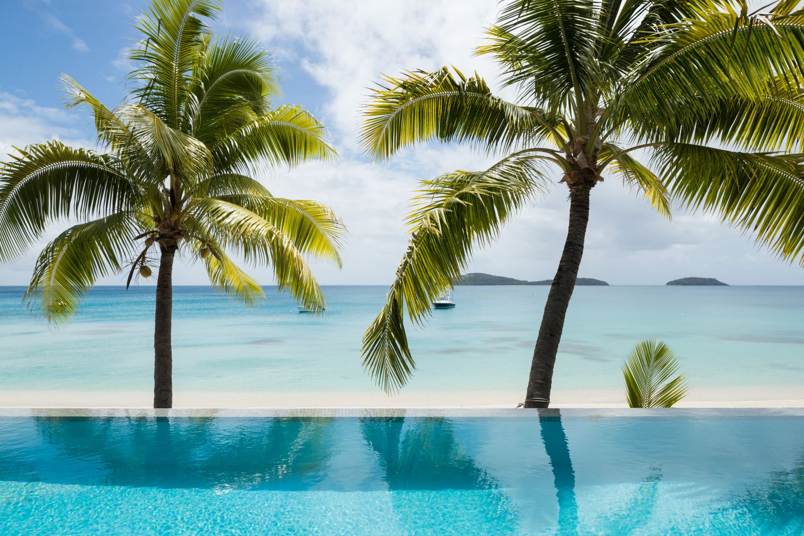 View over a villa pool and the palm-strewn beach to the Pacific Ocean at luxury resort Kokomo Island in Fiji
