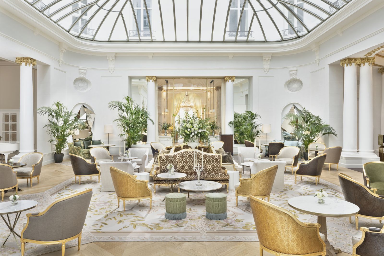 Glass-roofed palm court with palms and seating arrangements at luxury hotel Mandarin Oriental Ritz Madrid