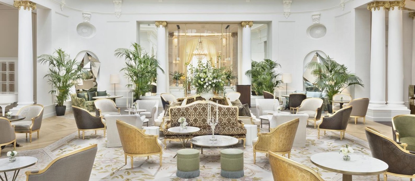 Glass-roofed palm court with palms and seating arrangements at luxury hotel Mandarin Oriental Ritz Madrid