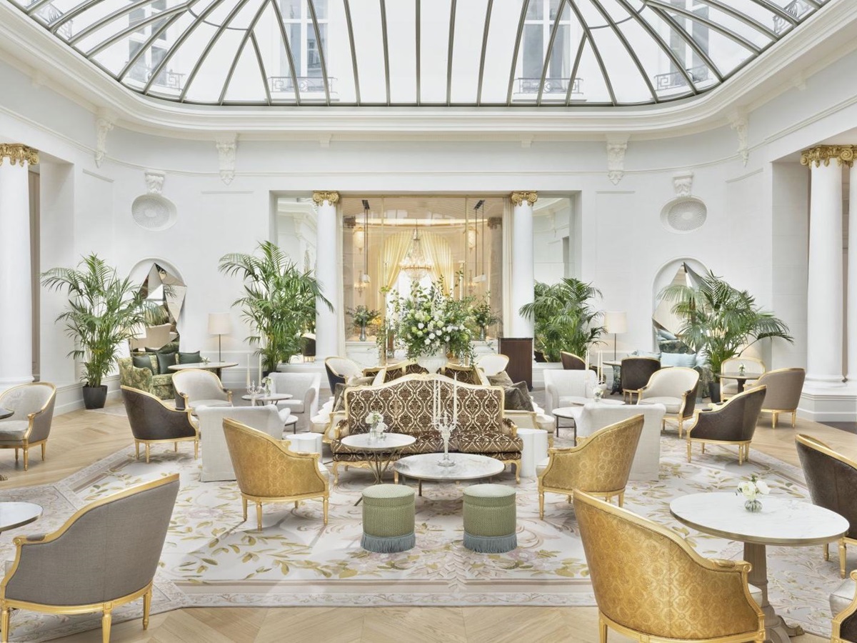 Glass-roofed palm court with palms and seating arrangements at luxury hotel Mandarin Oriental Ritz Madrid