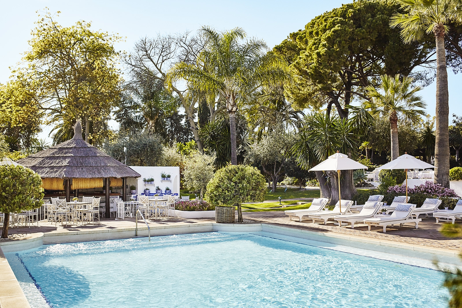 Loungers and parasols at the garden pool of luxury resort Marbella Club in Spain