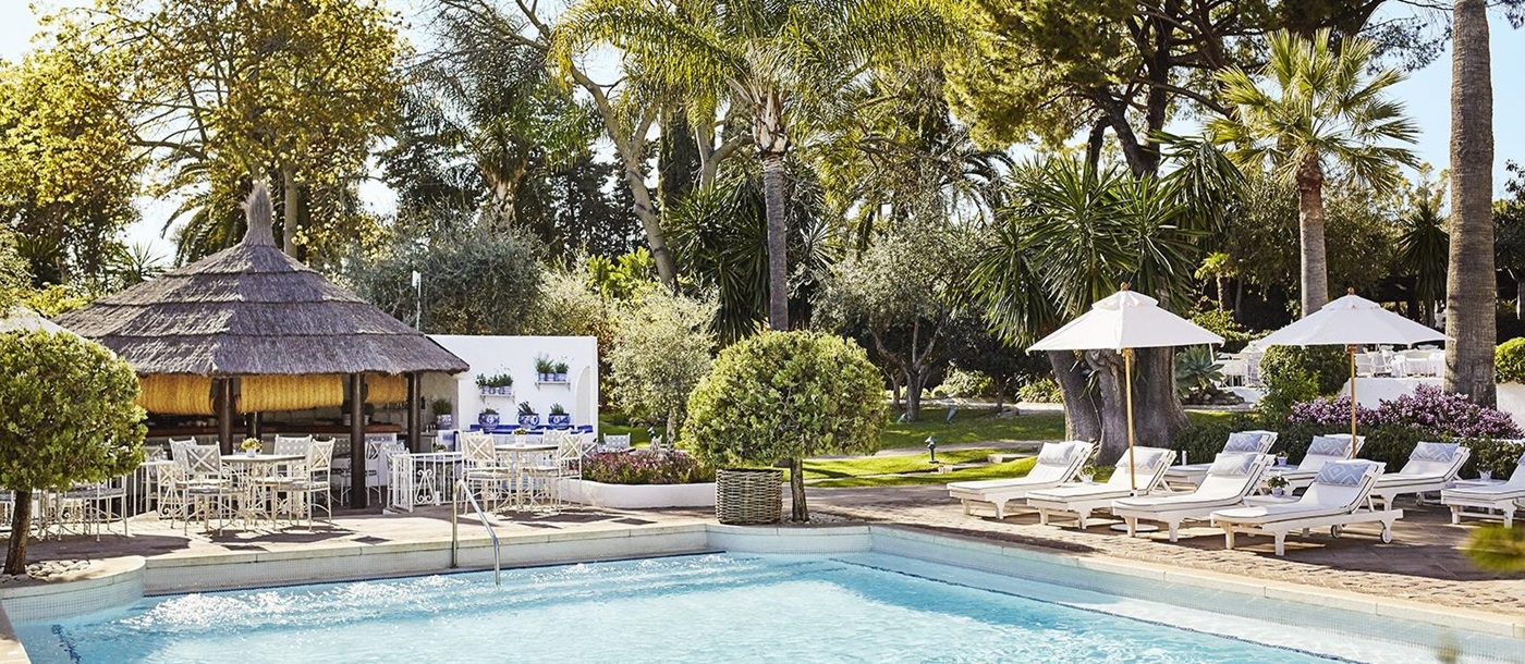 Loungers and parasols at the garden pool of luxury resort Marbella Club in Spain