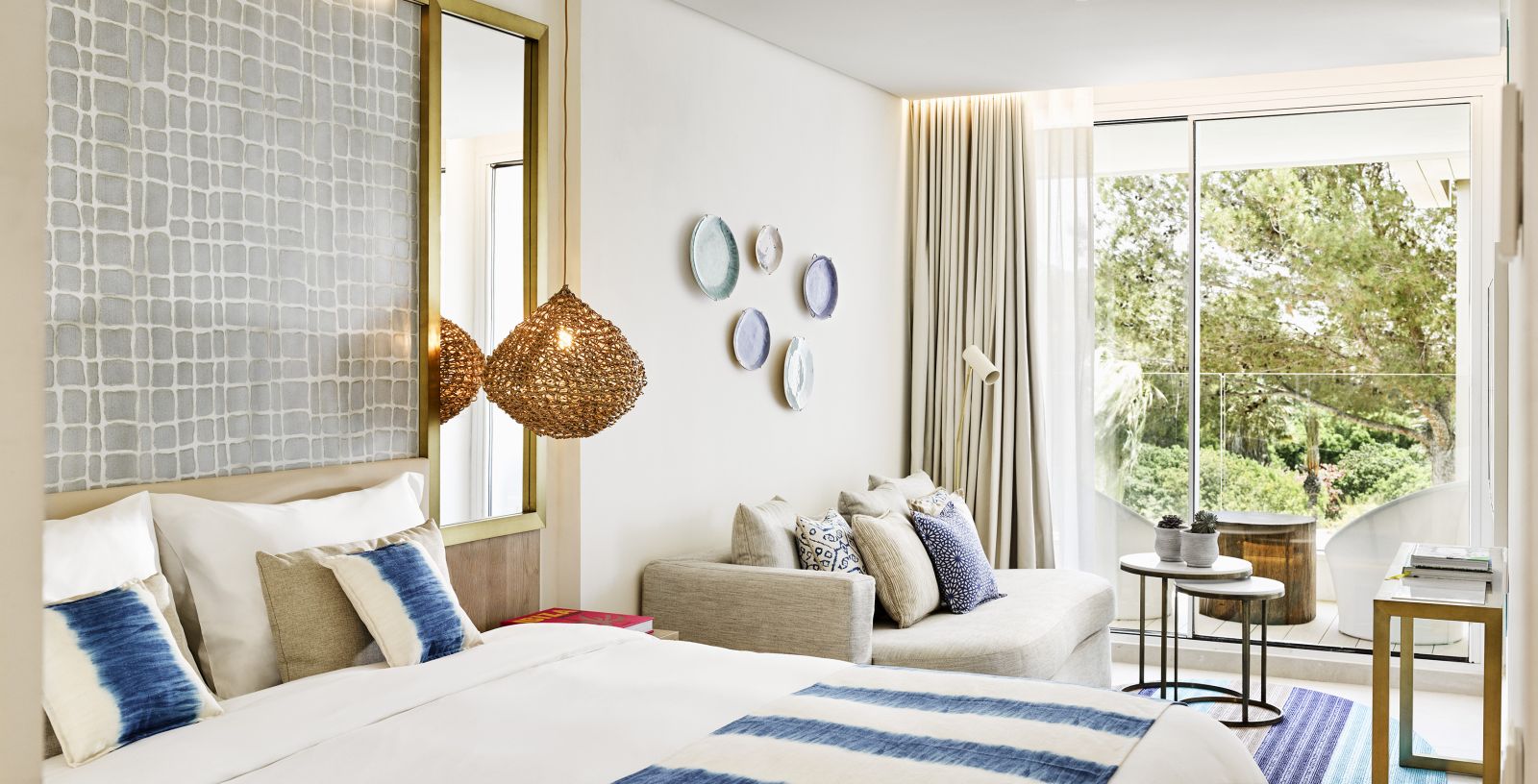 Spacious deluxe room with seating area and private balcony overlooking the gardens at luxury hotel Nobu Ibiza