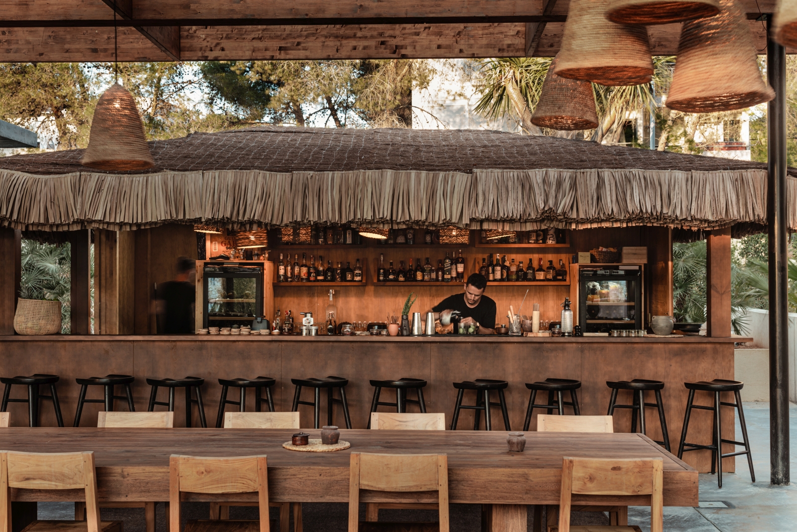 Bartender working at a straw-roofed bar at luxury resort OKU Ibiza