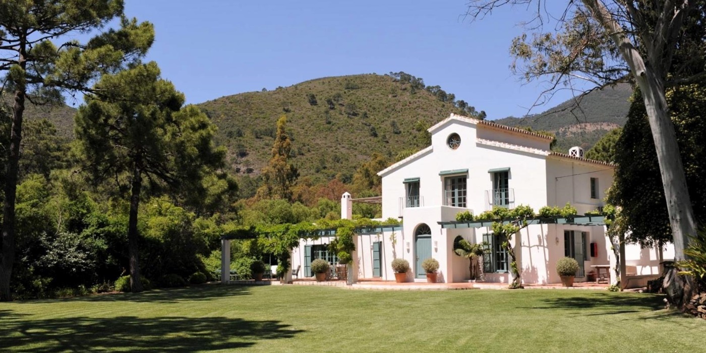 Façade and garden with trees, plants, vines and mountain view at Casa del Rio in Andalucia, Spain