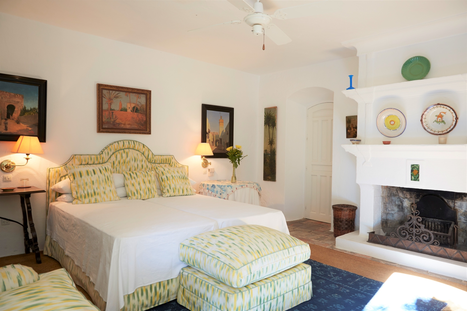 Bedroom with double bed, bedside tables, lamps, paintings and fireplace at Torre de Tramores in Andalucía, Spain