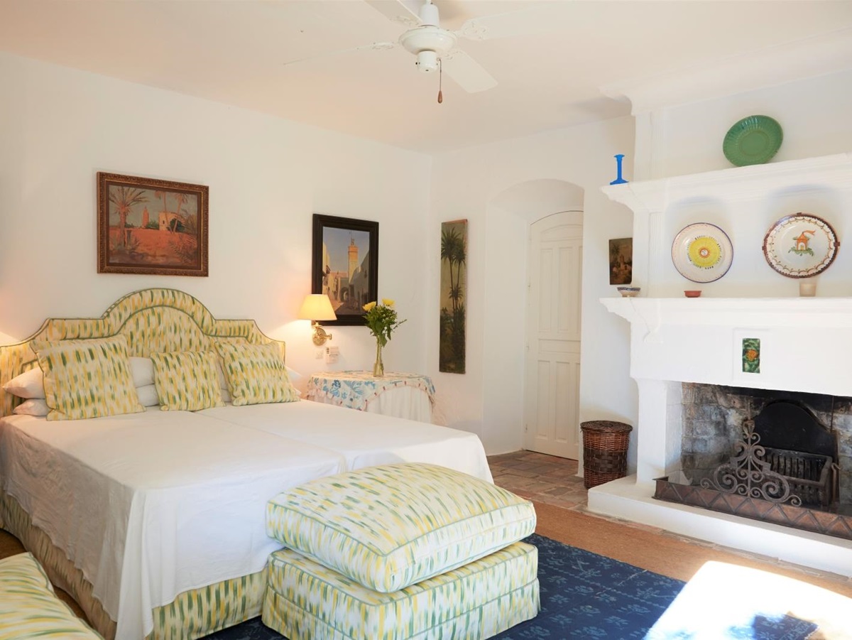 Bedroom with double bed, bedside tables, lamps, paintings and fireplace at Torre de Tramores in Andalucía, Spain