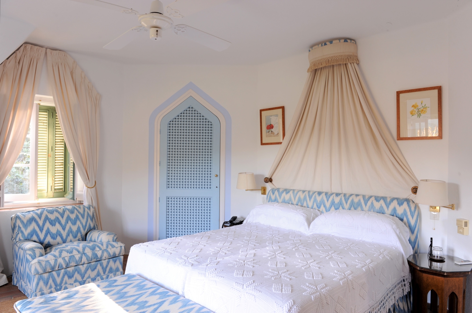 Bedroom with double bed, bedside tables, lamps, picture frames and armchair at Torre de Tramores in Andalucía, Spain