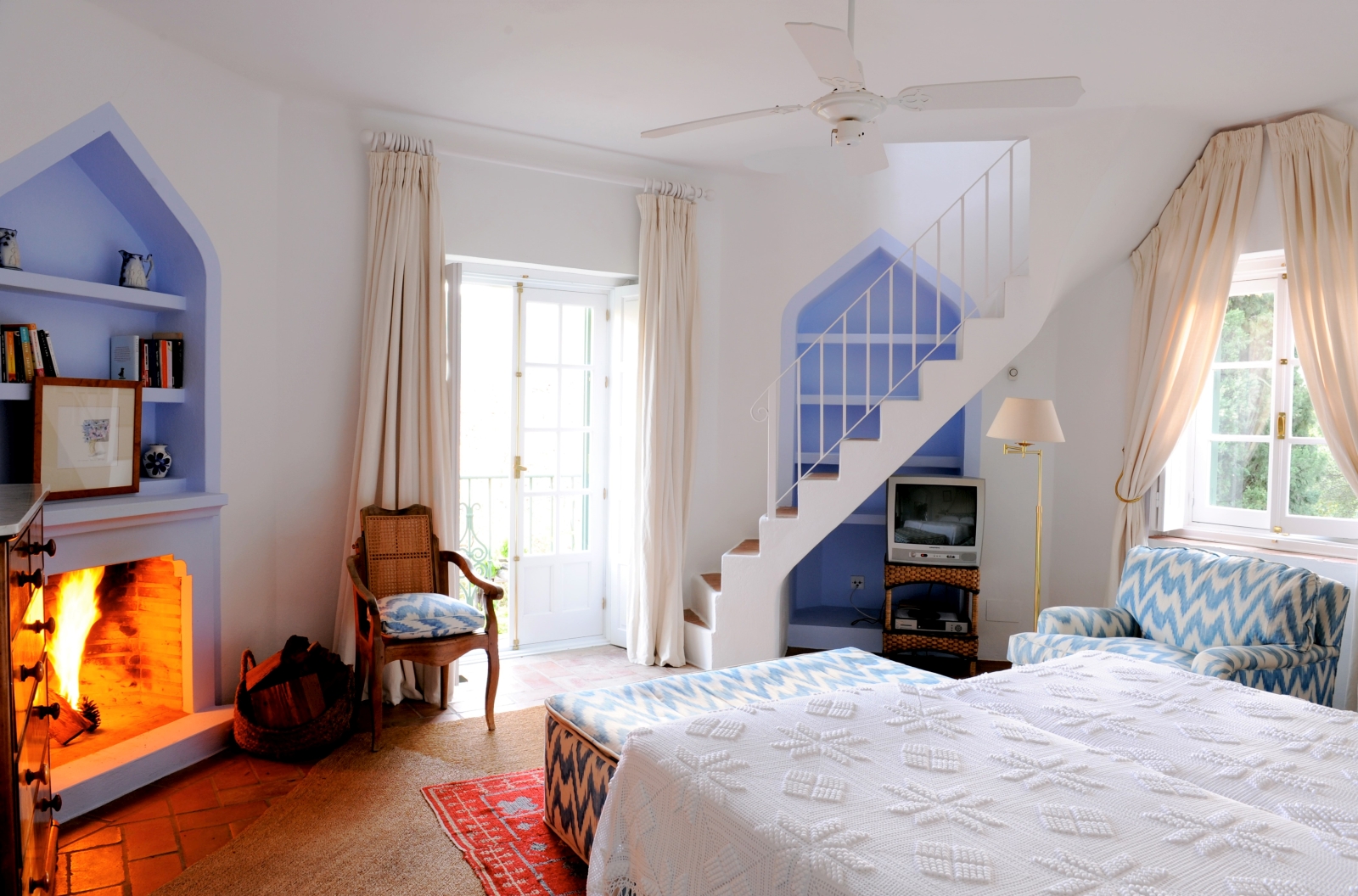 Bedroom with double bed, armchairs, TV, staircase, fireplace and French doors at Torre de Tramores in Andalucía, Spain