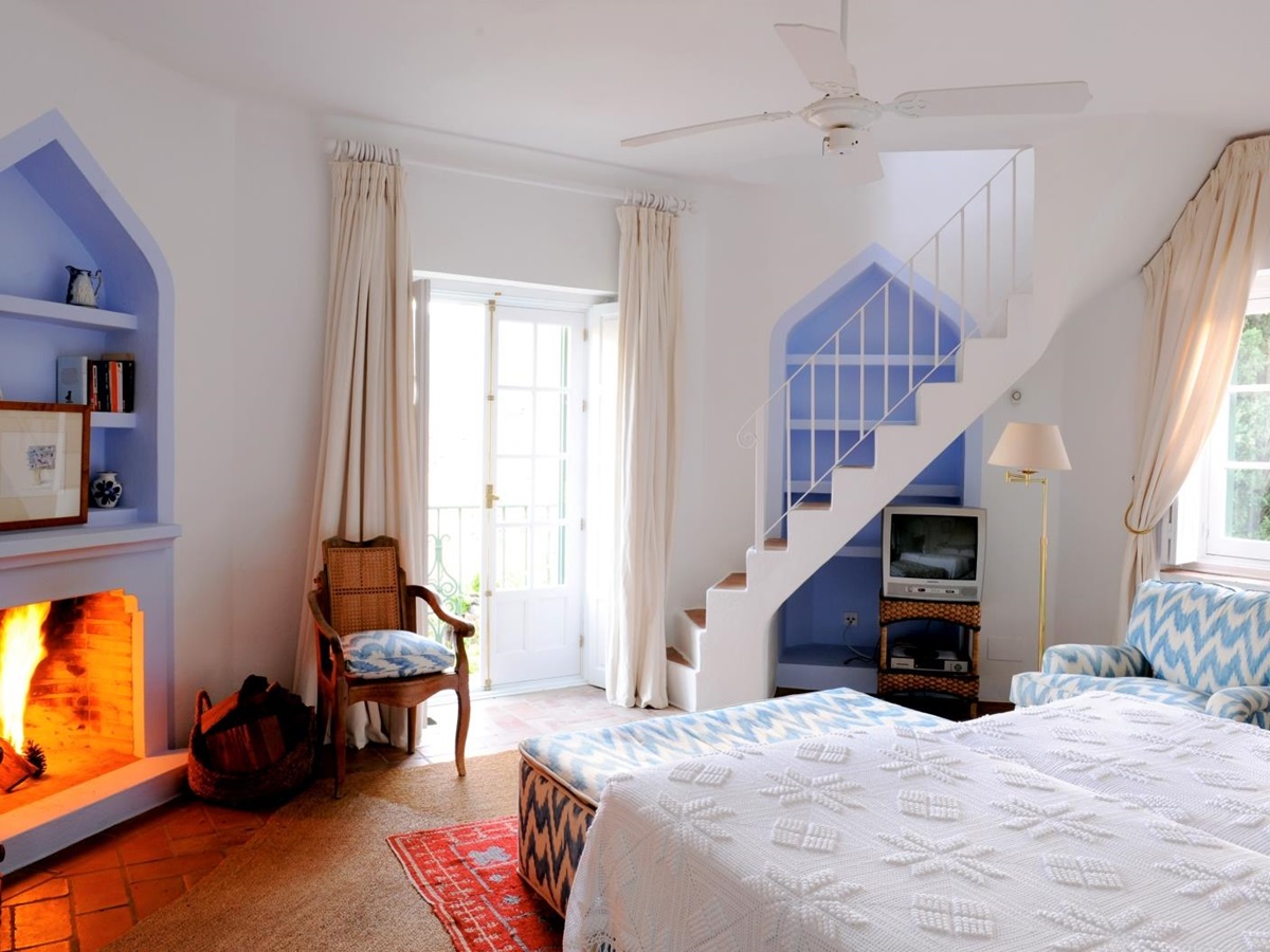 Bedroom with double bed, armchairs, TV, staircase, fireplace and French doors at Torre de Tramores in Andalucía, Spain