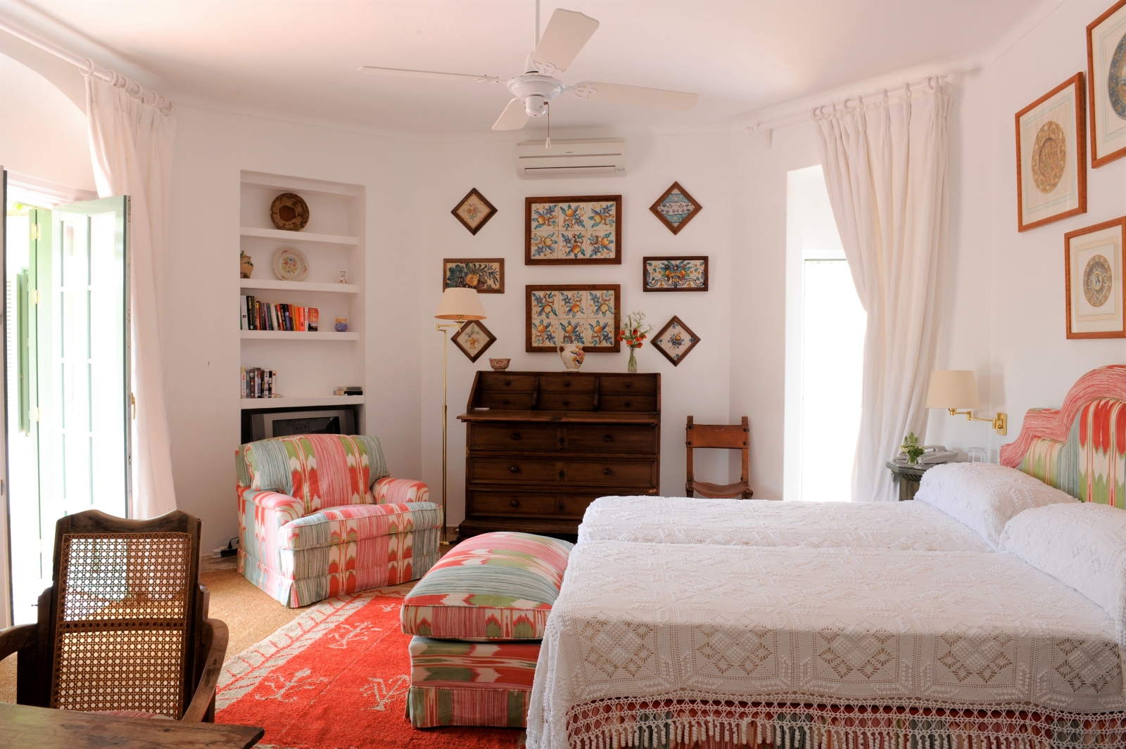 Bedroom with double bed, lamp, drawers, armchair, picture frames and French doors at Torre de Tramores in Andalucía, Spain