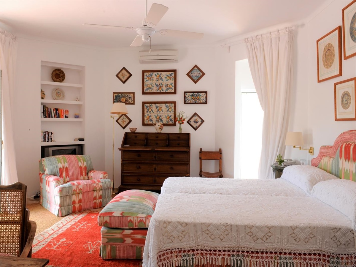 Bedroom with double bed, lamp, drawers, armchair, picture frames and French doors at Torre de Tramores in Andalucía, Spain