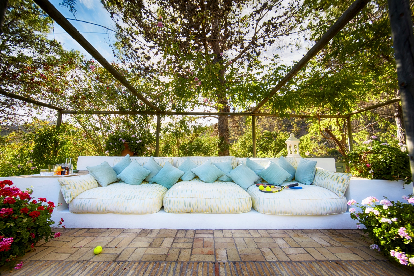 Outdoor lounge area with long sofa, plants and flowers at Torre de Tramores in Andalucía, Spain