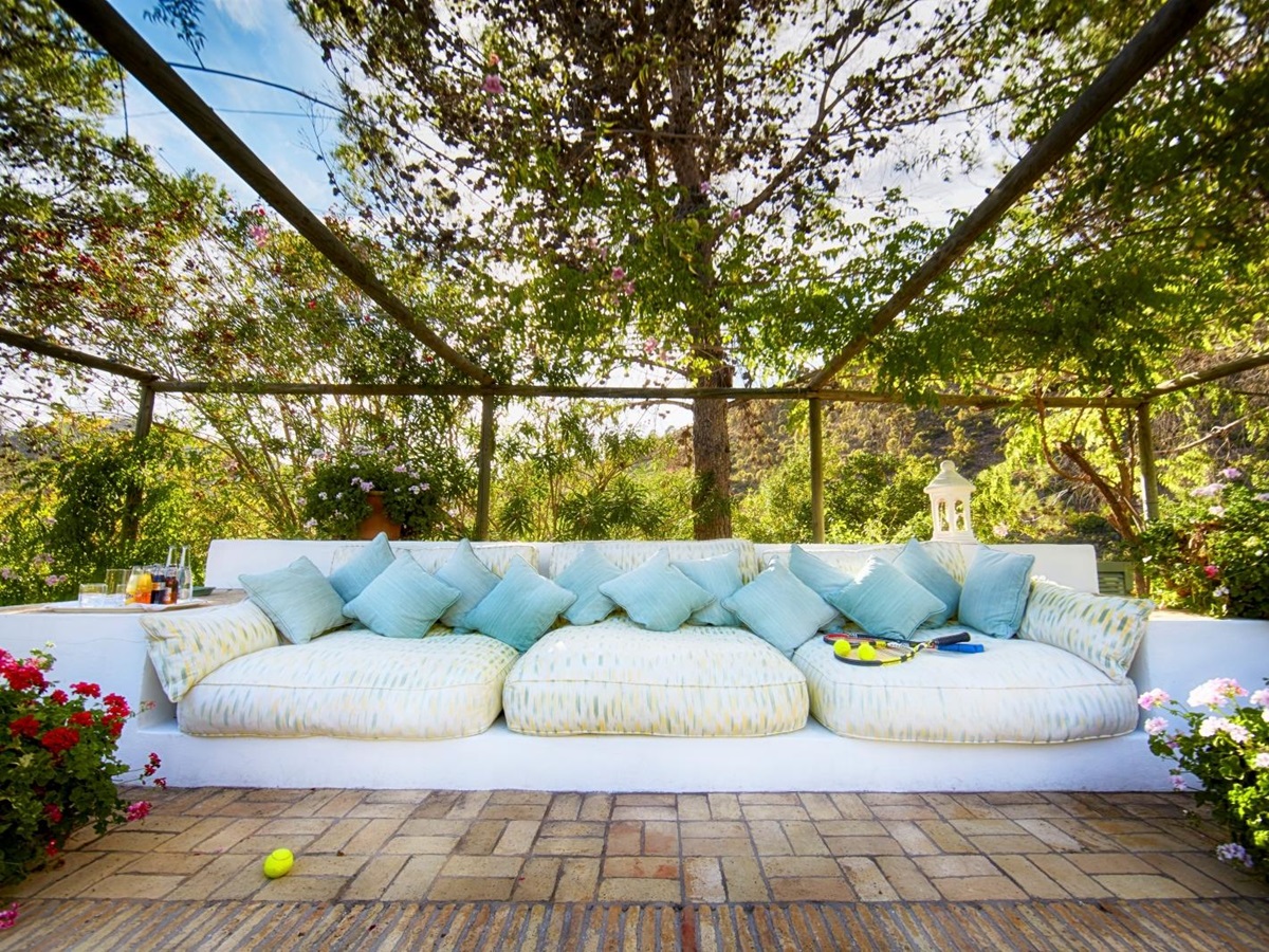 Outdoor lounge area with long sofa, plants and flowers at Torre de Tramores in Andalucía, Spain