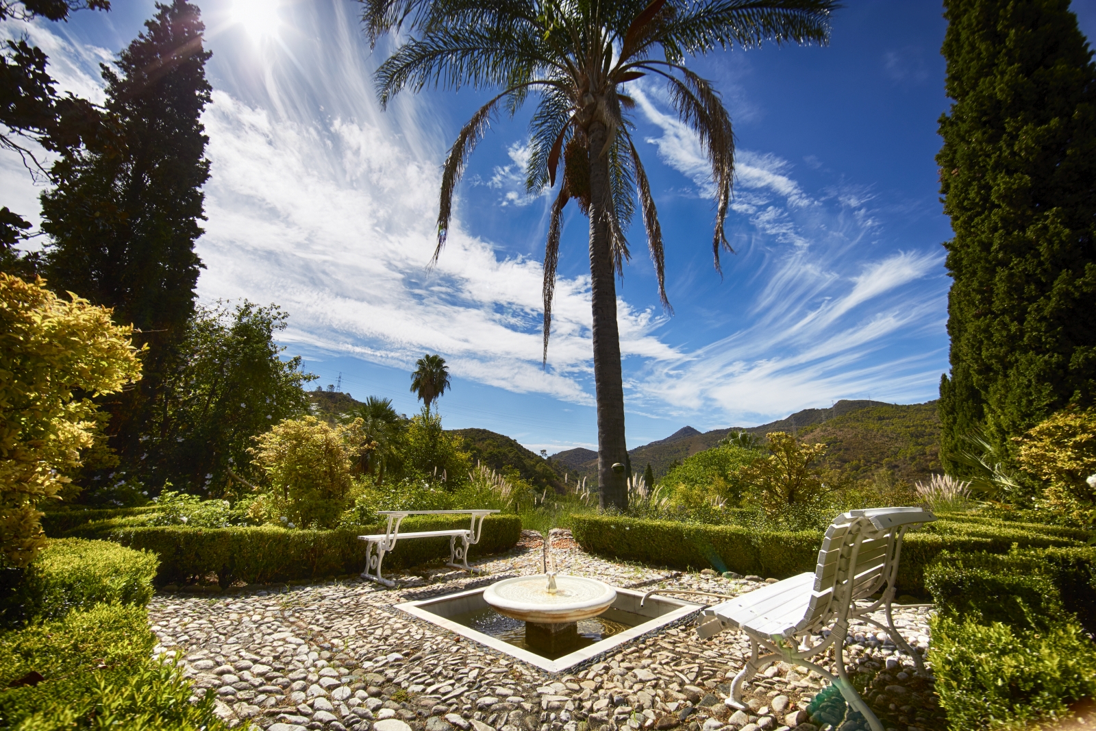 Patio with benches, fountain, plants, palm tree and countryside view at Torre de Tramores in Andalucía, Spain
