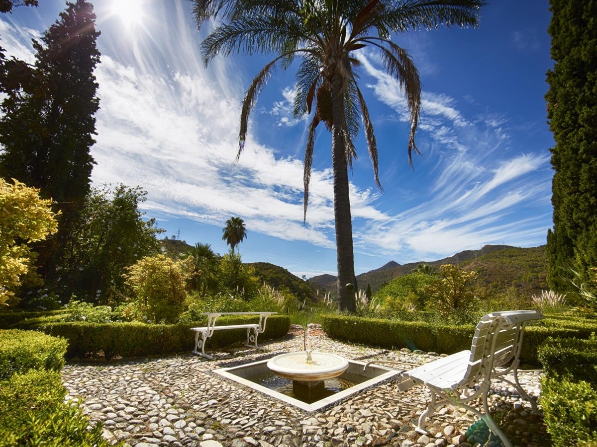 Patio with benches, fountain, plants, palm tree and countryside view at Torre de Tramores in Andalucía, Spain