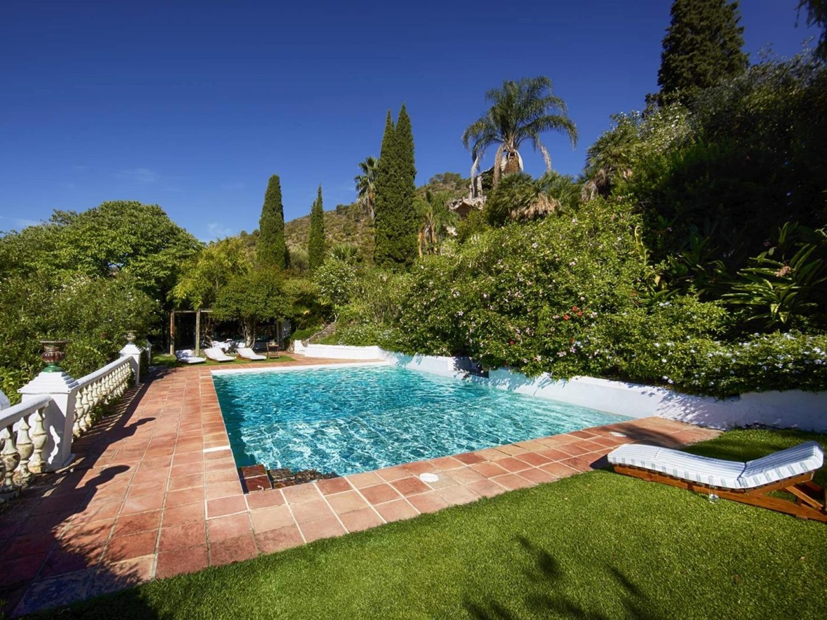 Pool and pool area with sun loungers, grass, terracotta tiles and plants at Torre de Tramores in Andalucía, Spain