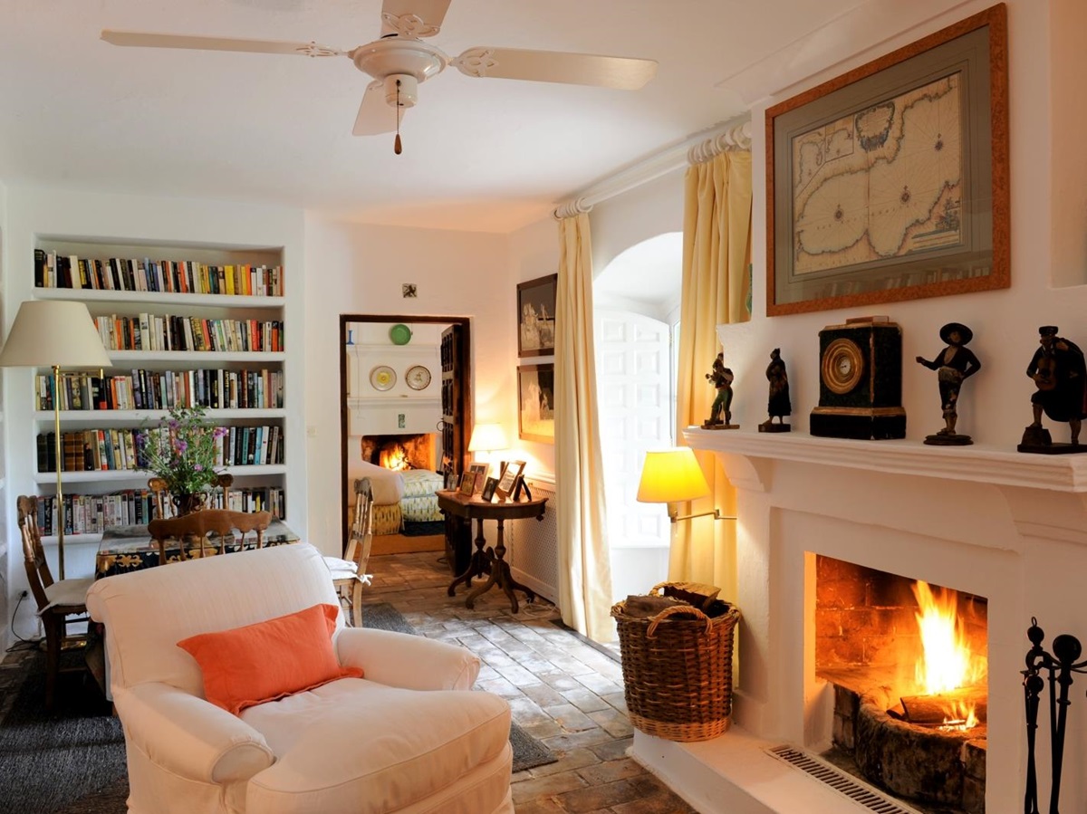 Study with fireplace, armchair, table chairs and bookcases at Torre de Tramores in Andalucía, Spain