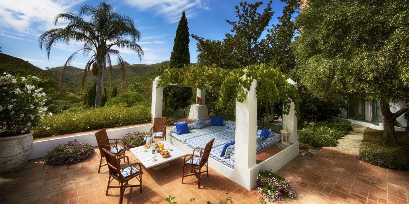 Terrace with coffee table, chairs, day bed, flowers and mountain view at Torre de Tramores in Andalucía, Spain