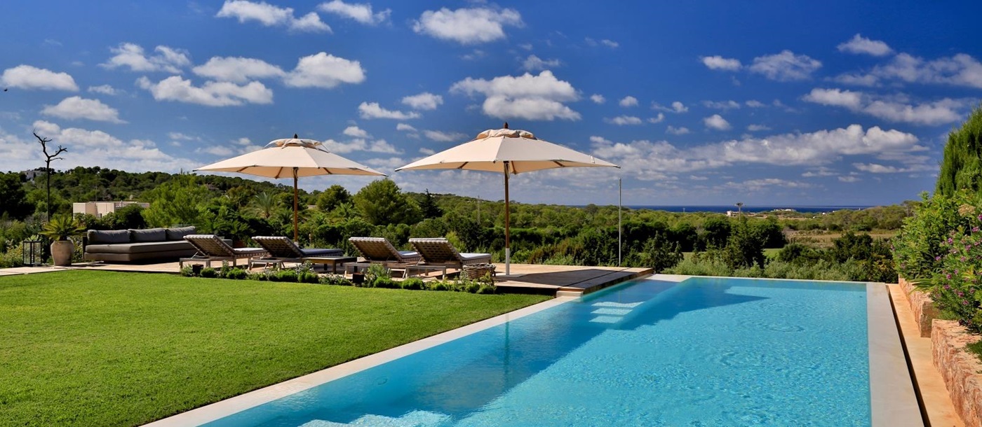 Pool and garden with sun loungers, umbrellas and sea view at Cala Comte in Ibiza, Spain