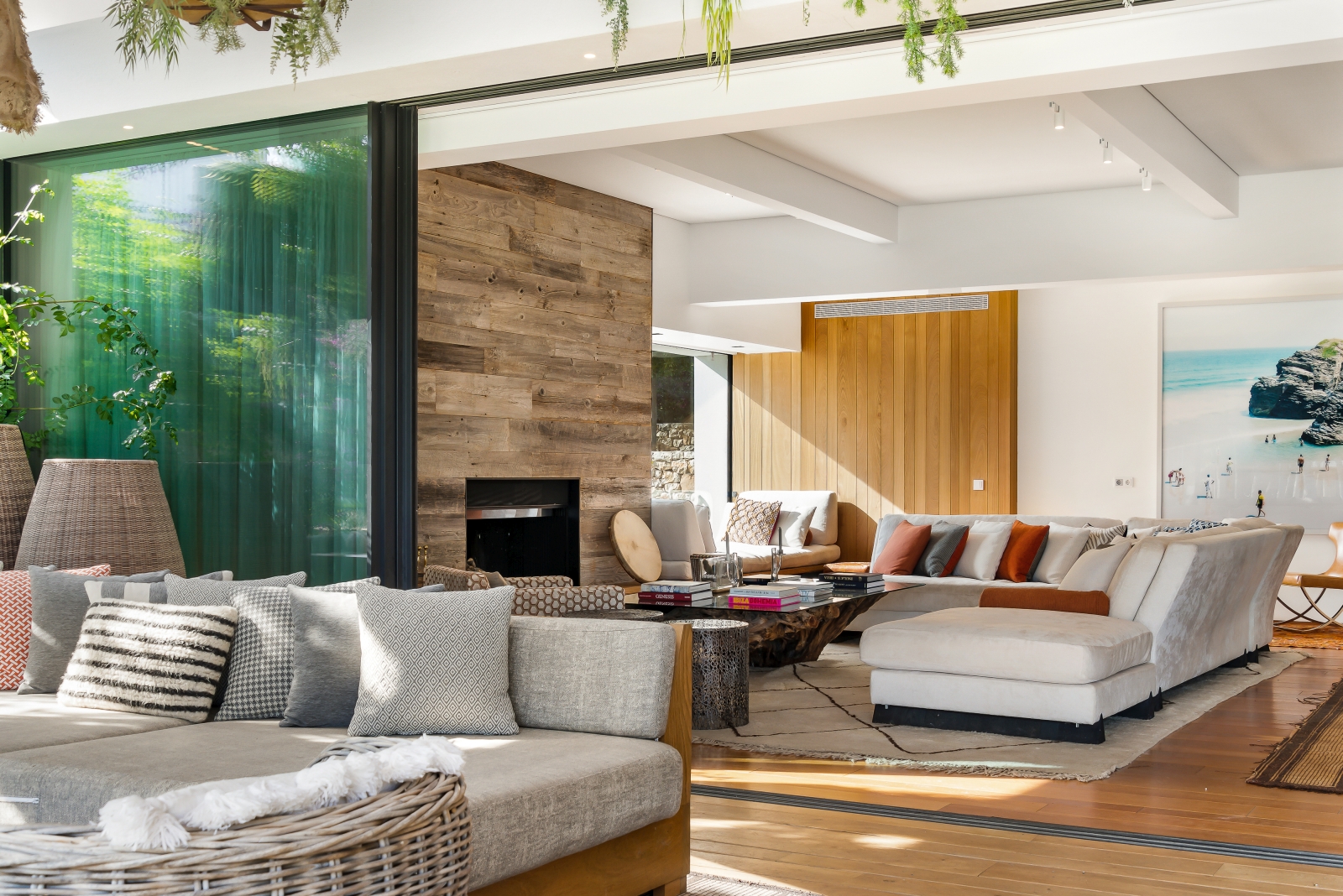 Looking over the outdoor lounge area into the living room with fire place and comfortable seating