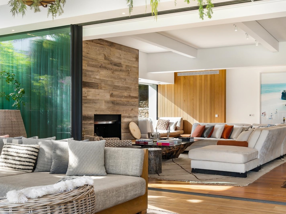 Looking over the outdoor lounge area into the living room with fire place and comfortable seating