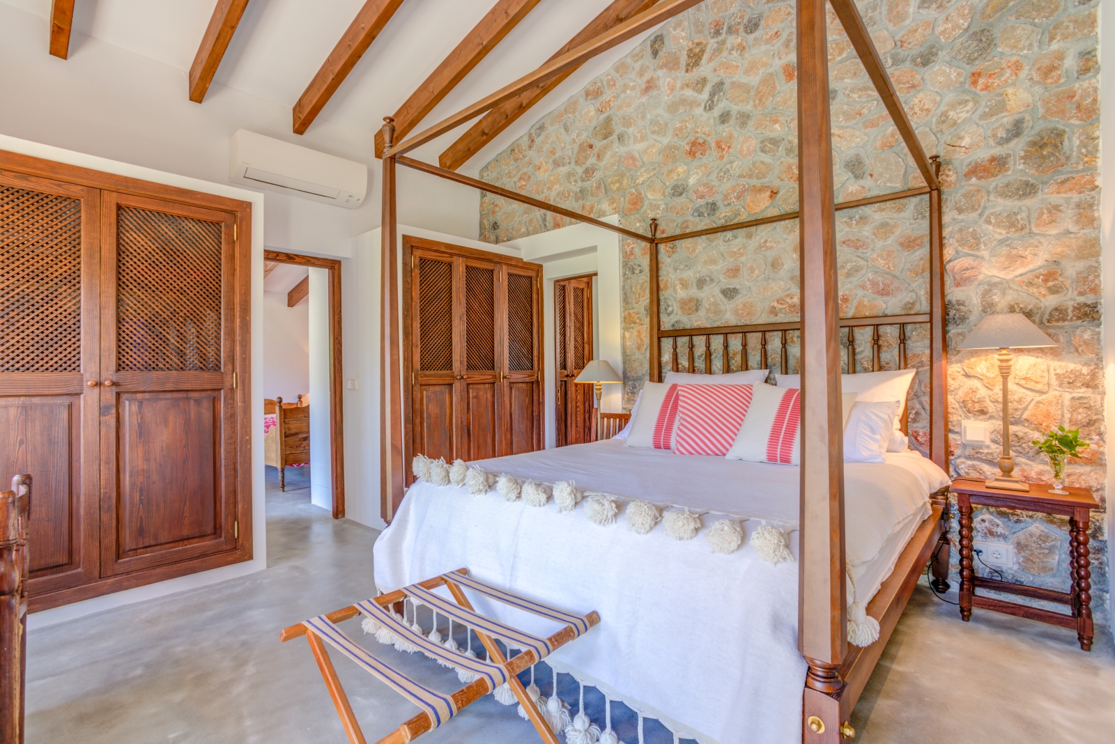 Double bedroom in annex with four-poster double bed, bedside table and stone wall at Can Canals in Mallorca, Spain