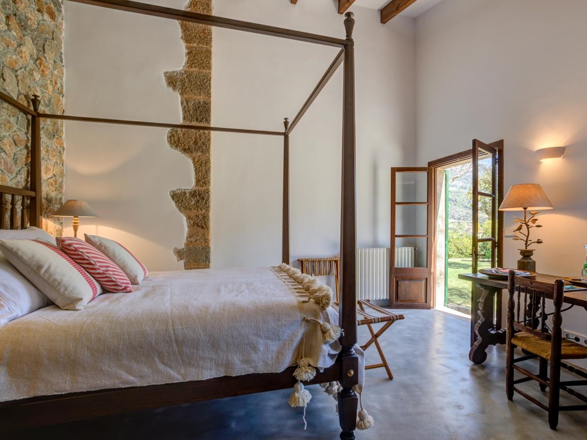 Double bedroom in annex with four-poster double bed, desk, chair, lamp and French doors at Can Canals in Mallorca, Spain