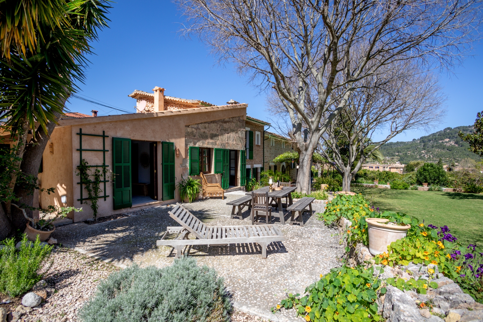 Patio and annex with lawn, trees and mountains in the background at Can Canals in Mallorca, Spain