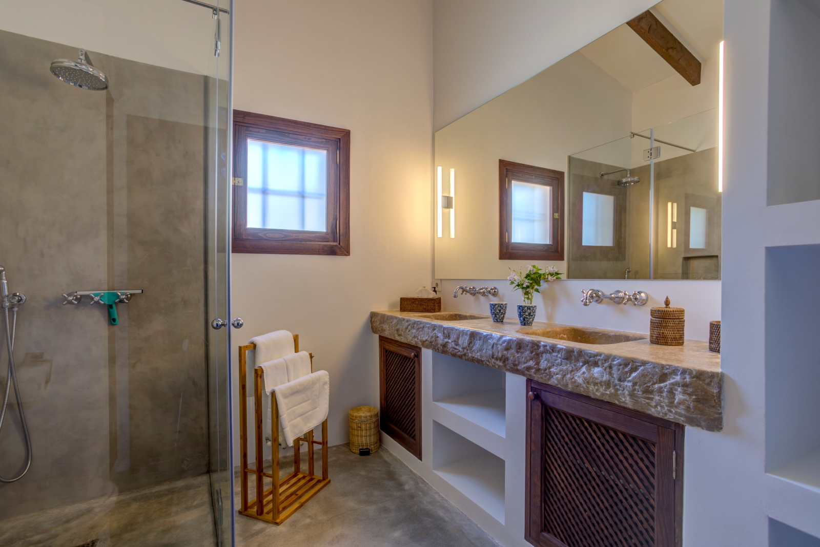 Bathroom with a shower, two sinks, a towel stand, a large mirror and a small window at Can Canals in Mallorca, Spain