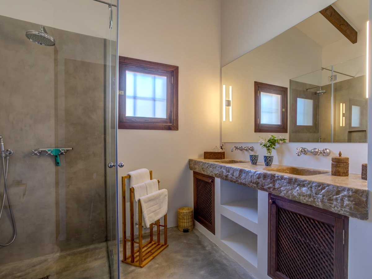Bathroom with a shower, two sinks, a towel stand, a large mirror and a small window at Can Canals in Mallorca, Spain
