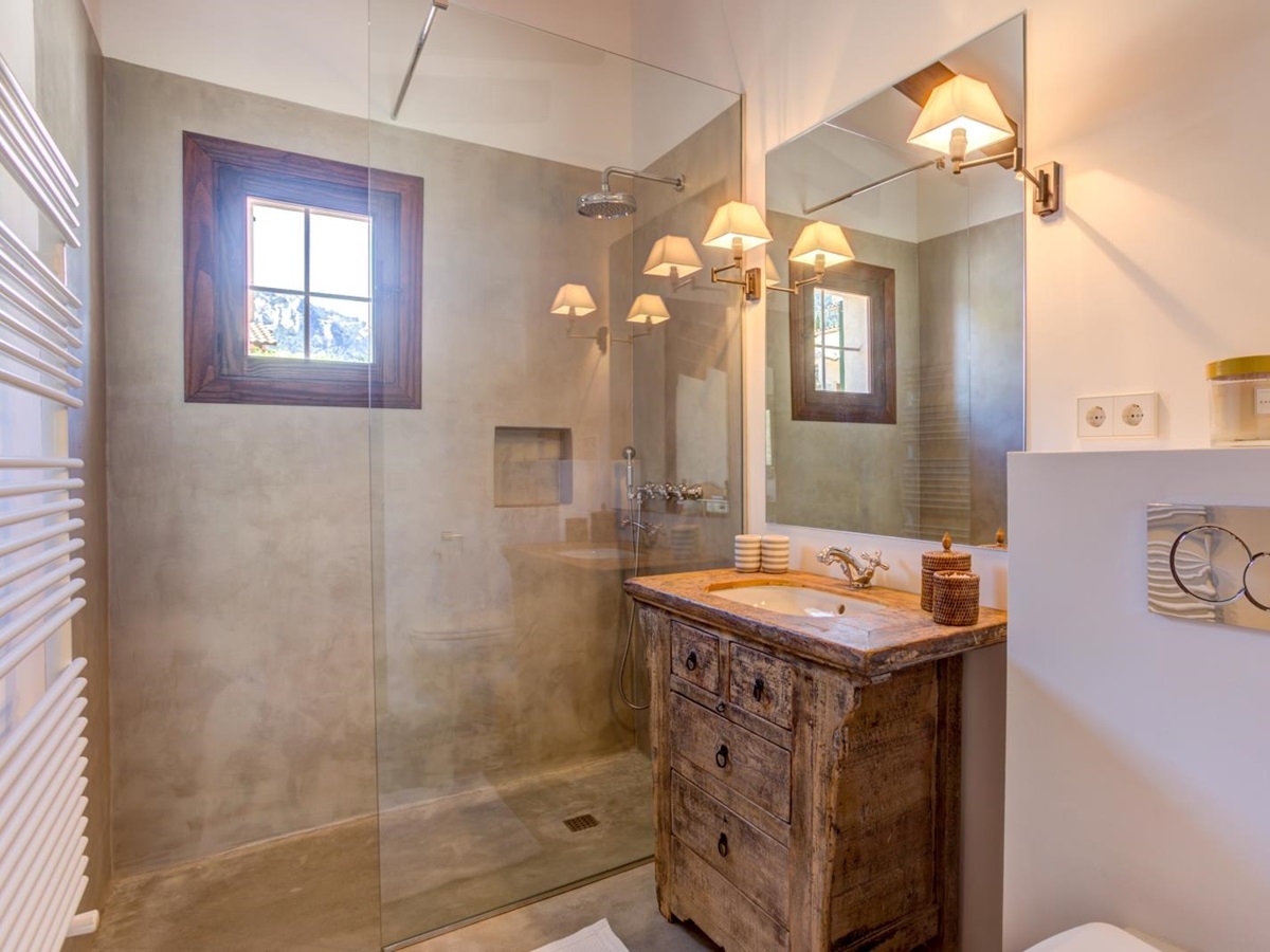 Bathroom with a shower, wooden sink unit, large mirror, towel rail, toilet and small window at Can Canals in Mallorca, Spain