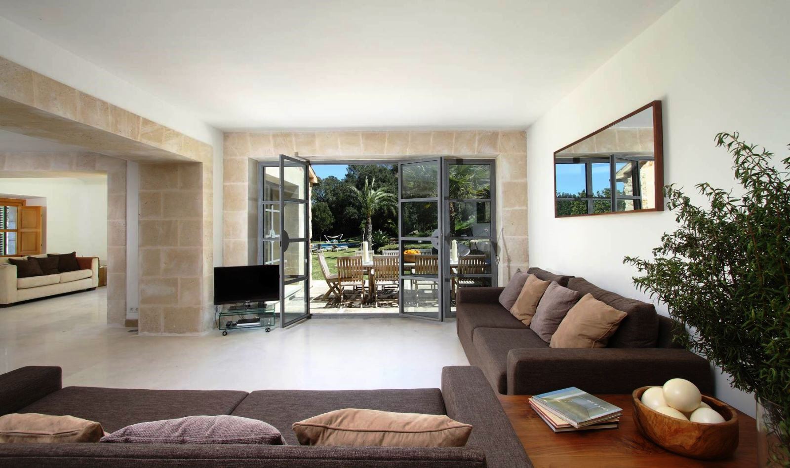 two brown sofas and tv in living room with big glass doors onto terrace at villa can jardine verde in Mallorca