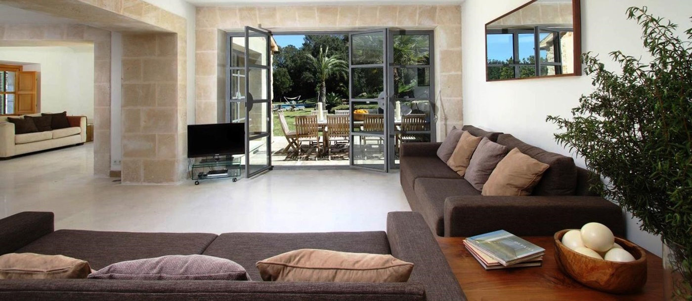 two brown sofas and tv in living room with big glass doors onto terrace at villa can jardine verde in Mallorca