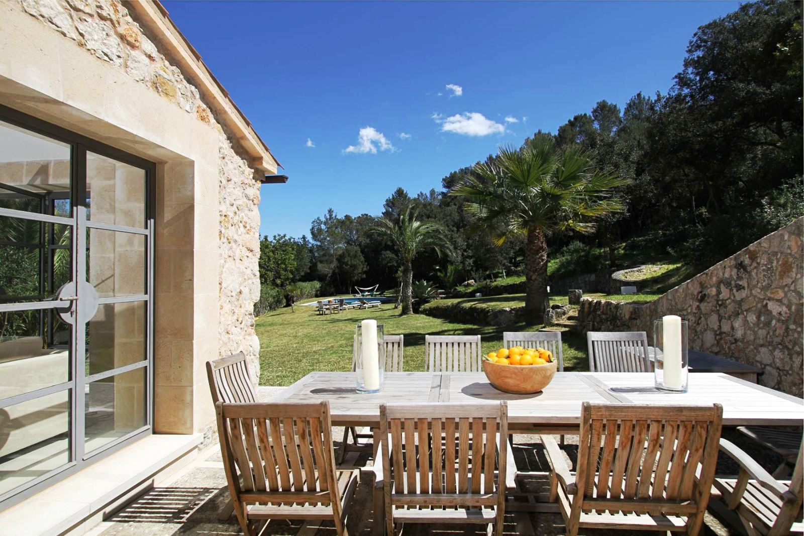 long wooden table and 9 chairs on terrace in garden at villa can jardine verde in Mallorca
