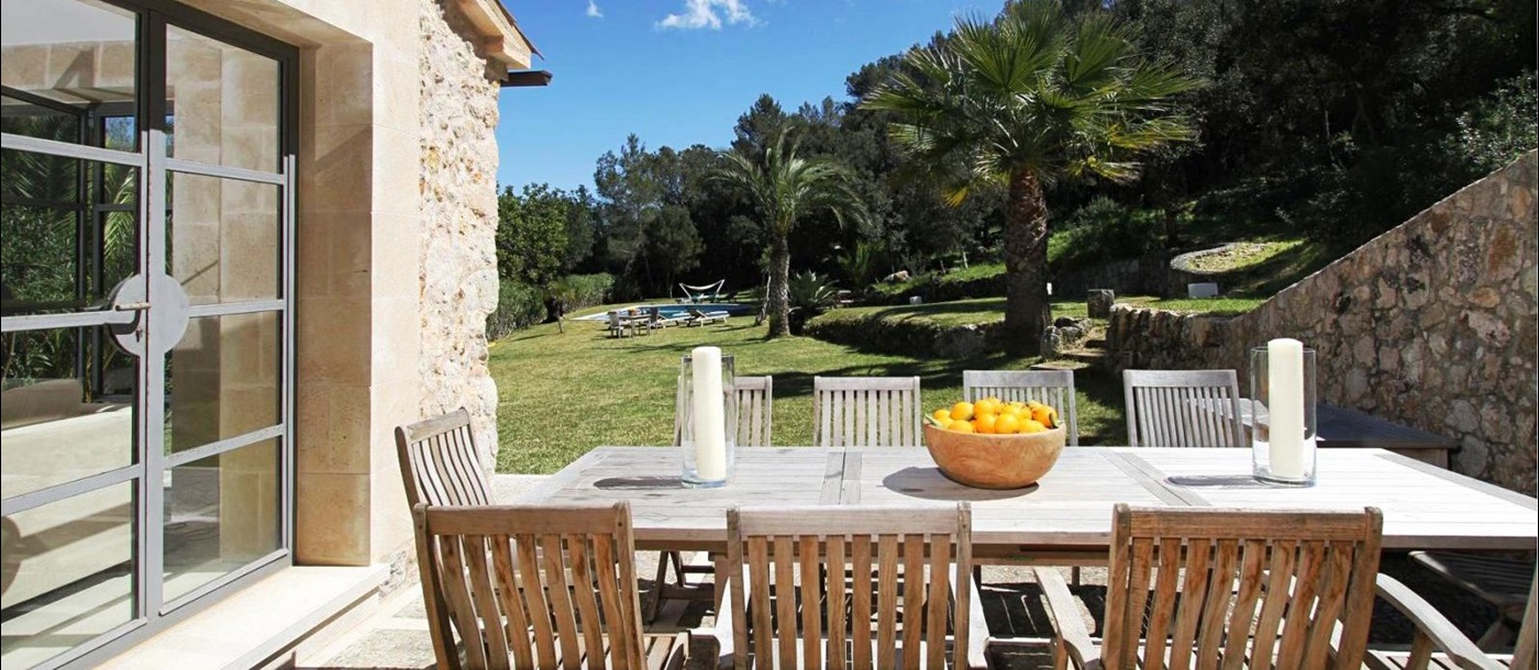 long wooden table and 9 chairs on terrace in garden at villa can jardine verde in Mallorca