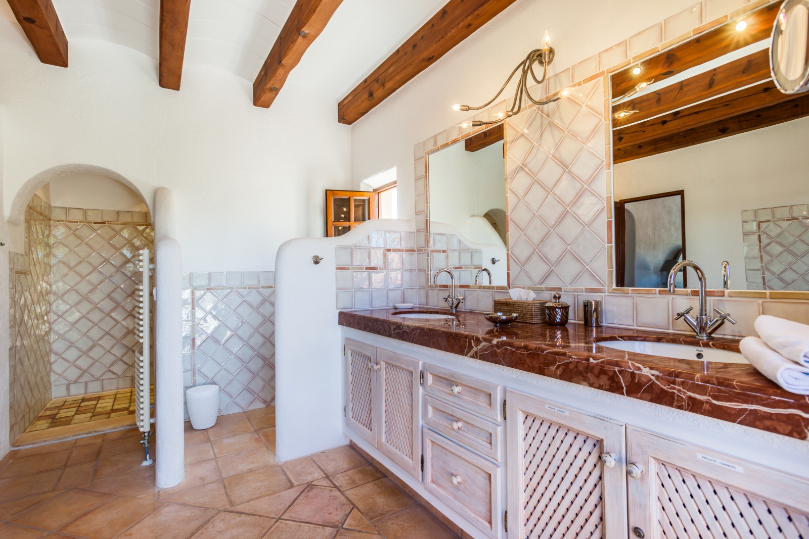 Bathroom with two sinks, two mirrors, shower room, towel rail and ceiling beams at Can Suelo in Mallorca, Spain