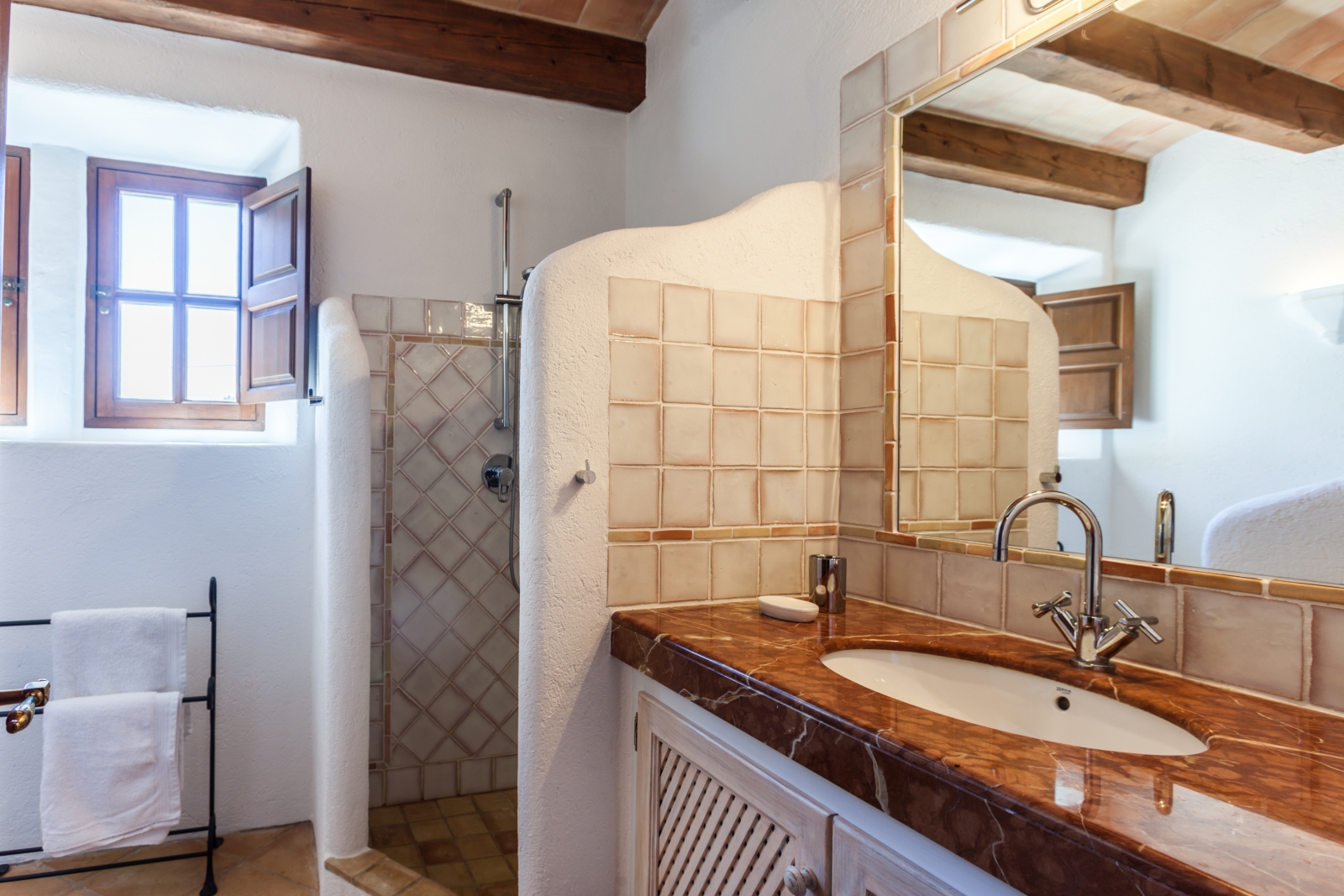 Bathroom with sink, large mirror, shower, towel rail and small windows at Can Suelo in Mallorca, Spain