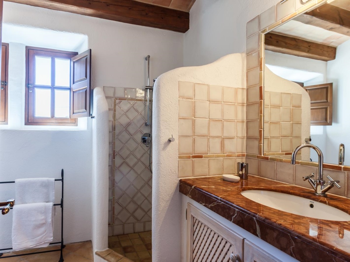 Bathroom with sink, large mirror, shower, towel rail and small windows at Can Suelo in Mallorca, Spain