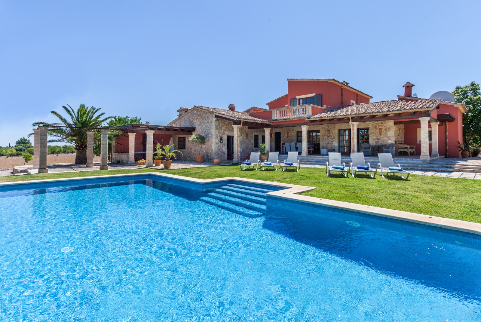 Pool with sun loungers and view of back of villa and garden at Can Suelo in Mallorca, Spain