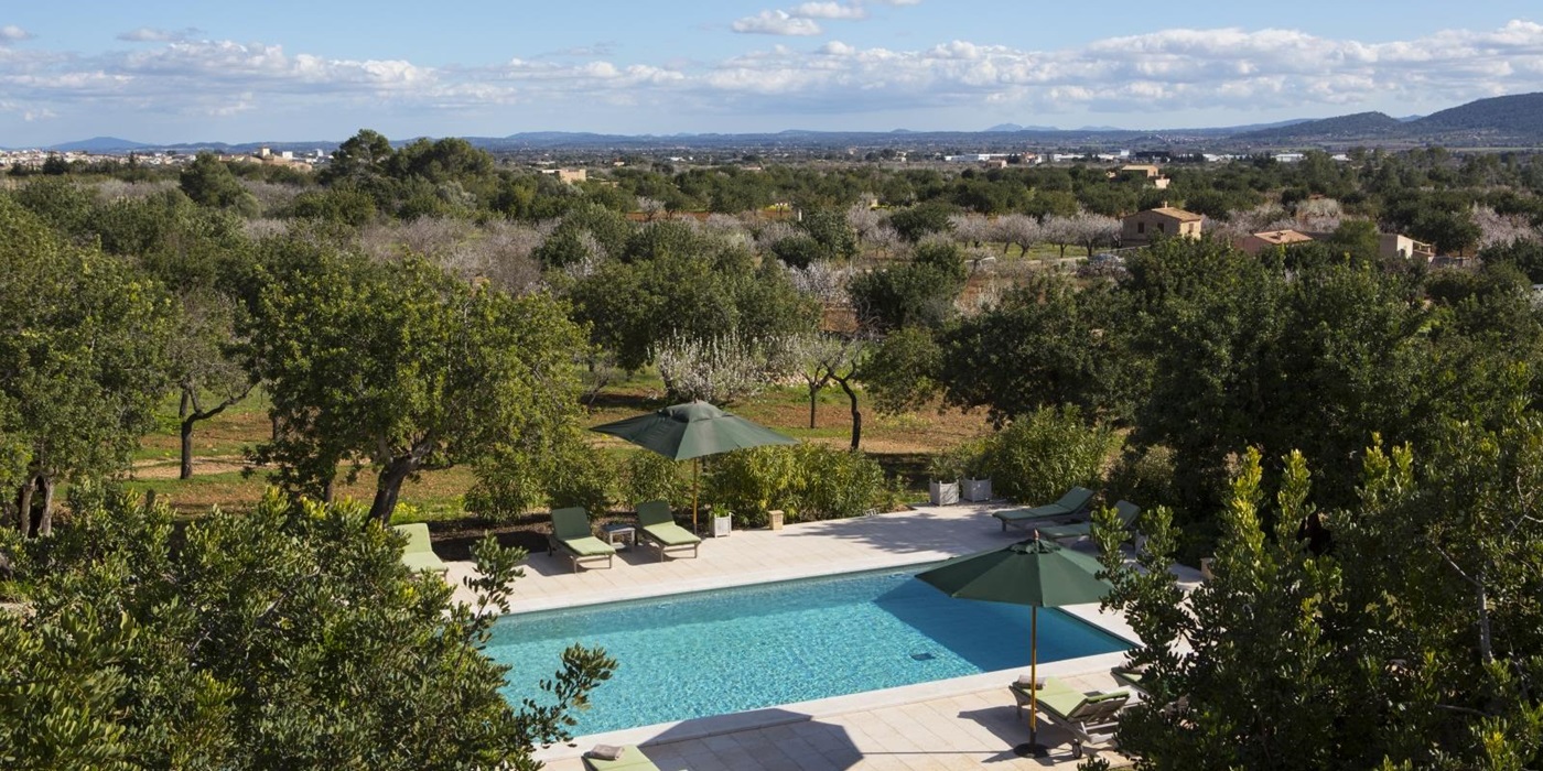 View over the pool and loungers with parasols at Casa Hermosa, luxury villa in Mallorca