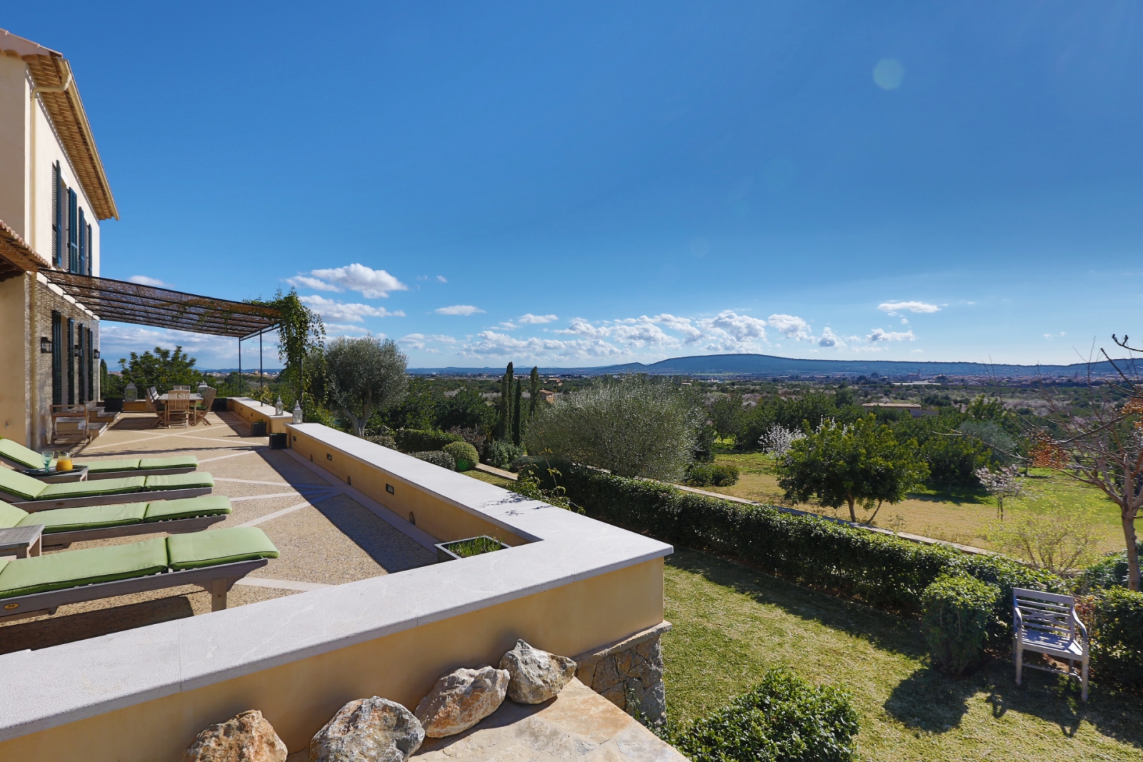 Terrace of luxury villa Casa Hermosa with loungers and shaded outdoor dining area and views over the Mallorcan countryside