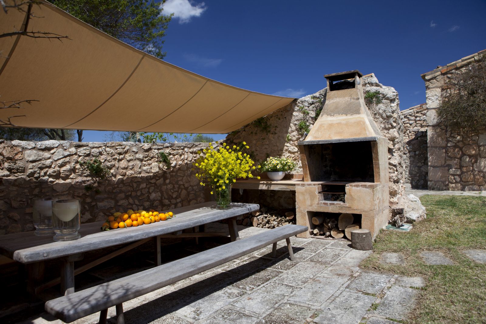 Long wooden table and bench on paved area in front of brick built BBQ at villa San Lorenzo in Mallorca