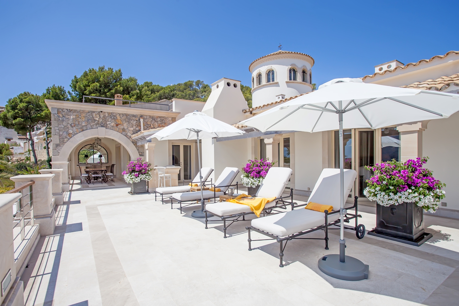 Terrace with sun loungers, umbrellas, flowers and covered dining area at Vista Marmessen in Mallorca, Spain