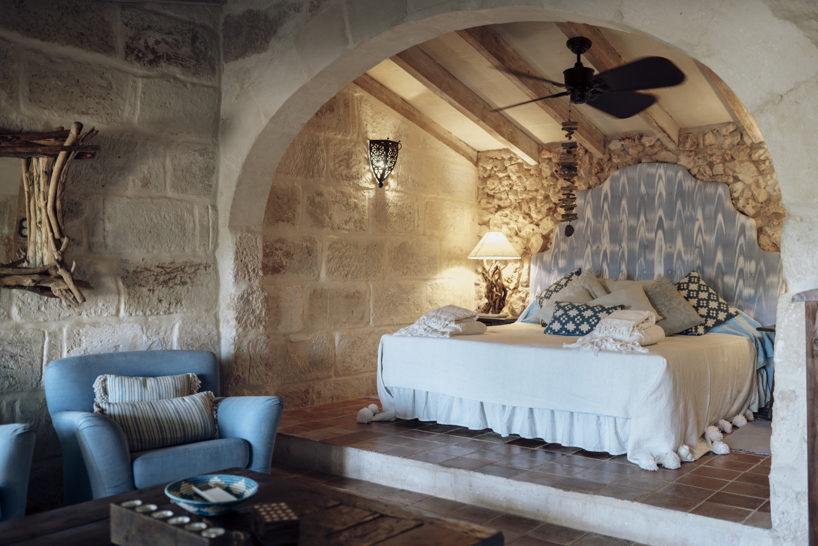 Bedroom with private seating area and bed in alcove under fan at luxury villa Binicalaf on Menorca