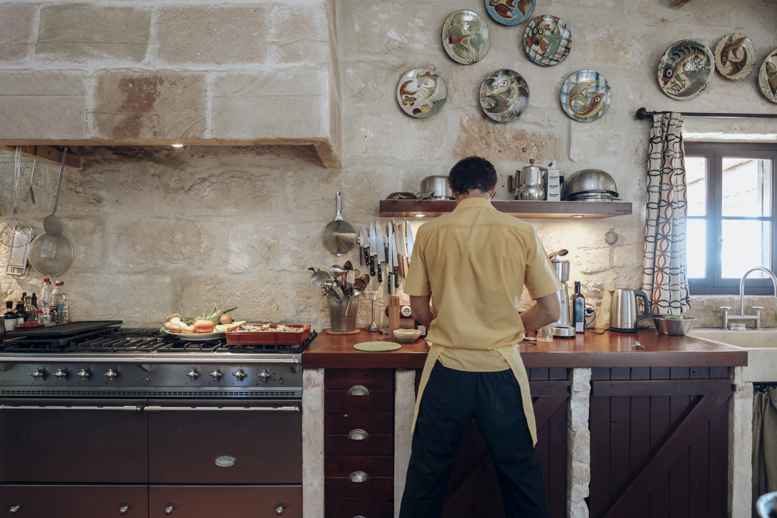 Chef preparing a meal in the rustic, fully-equipped kitchen at Menorcan luxury villa Binicalaf
