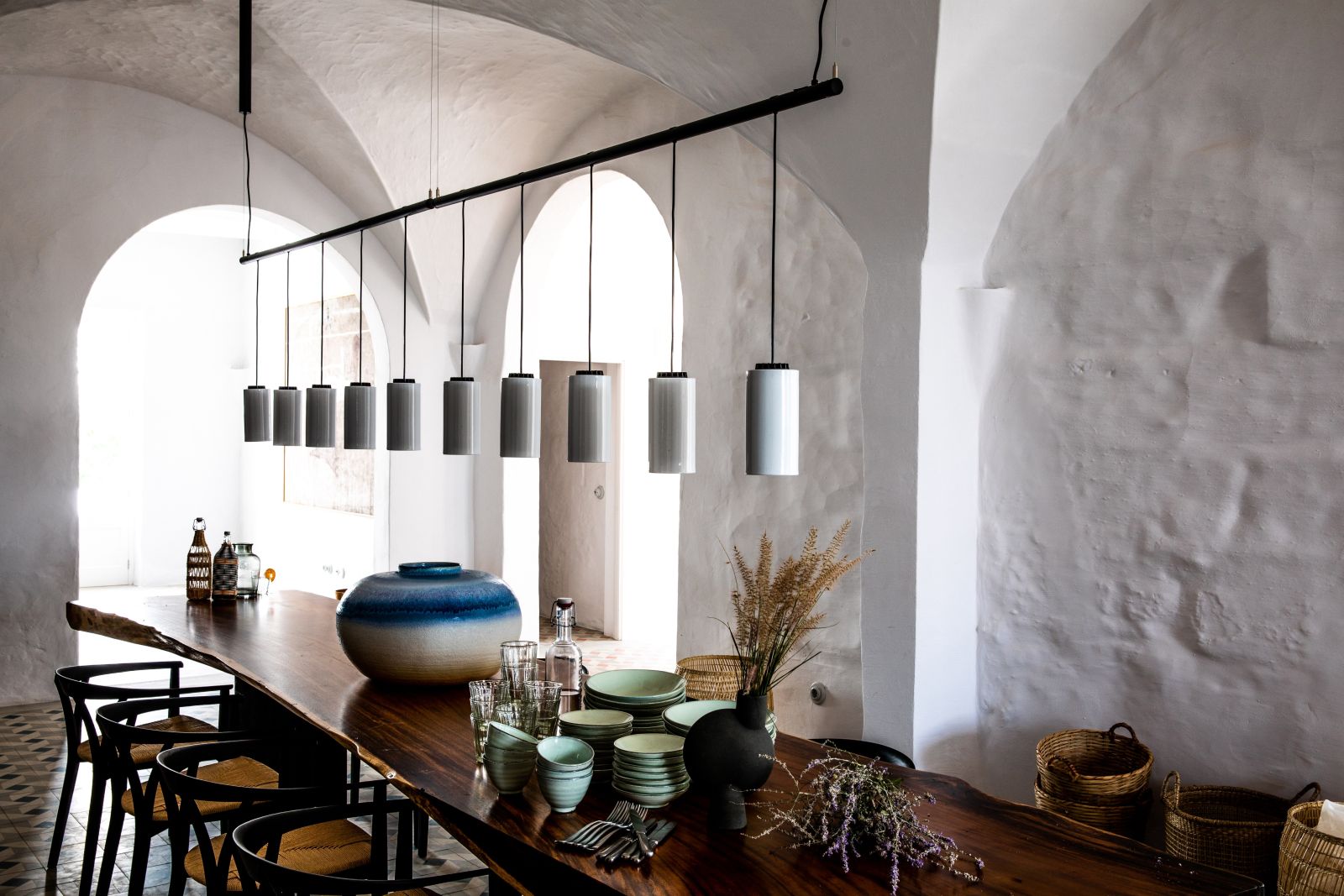 long wooden table with strip of lights hanging from ceiling and four chairs at luxury villa Casa Benedicta in Menorca