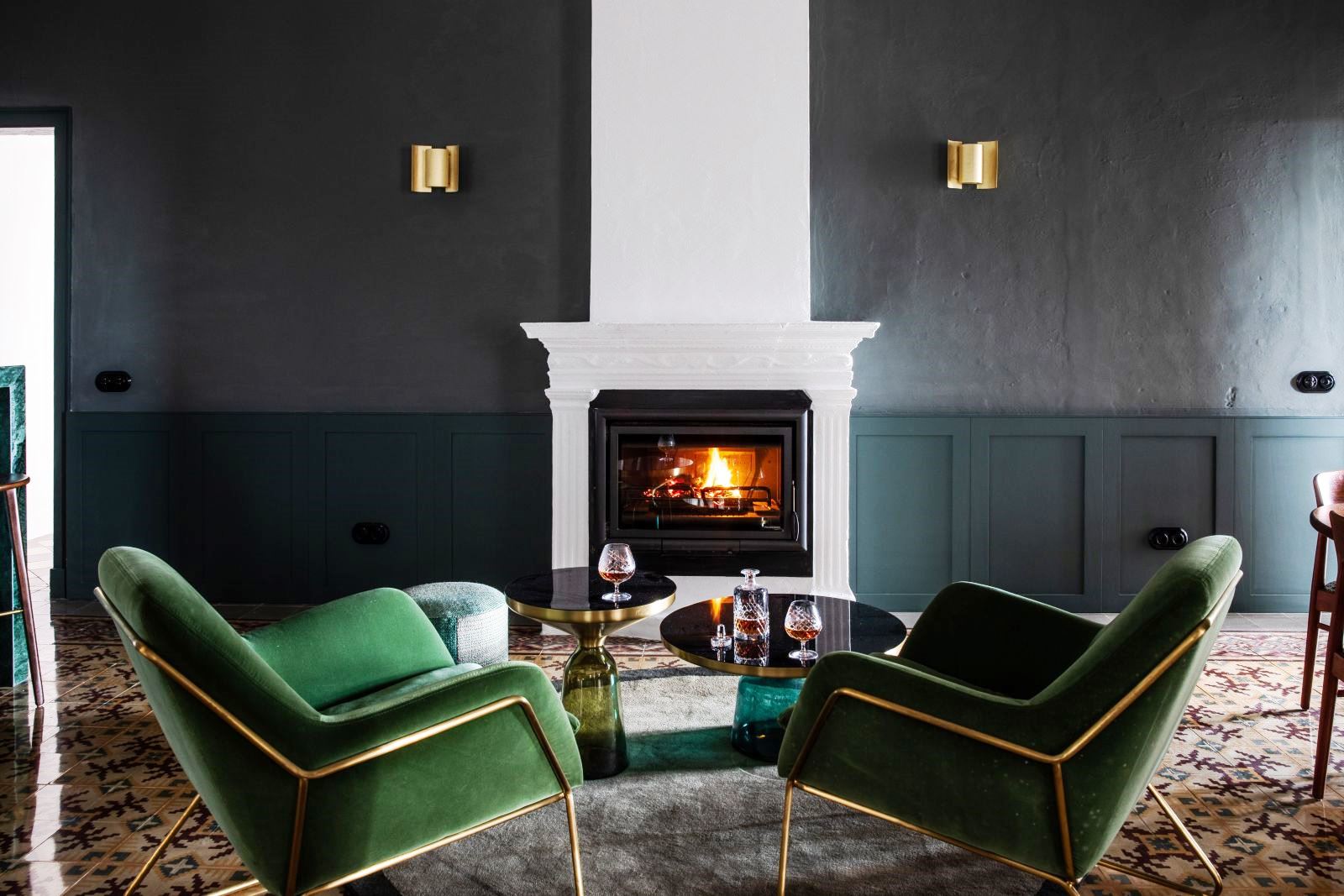 two green chairs and two round tables with brandy glasses in front of fire at luxury villa Casa Benedicta in Menorca 