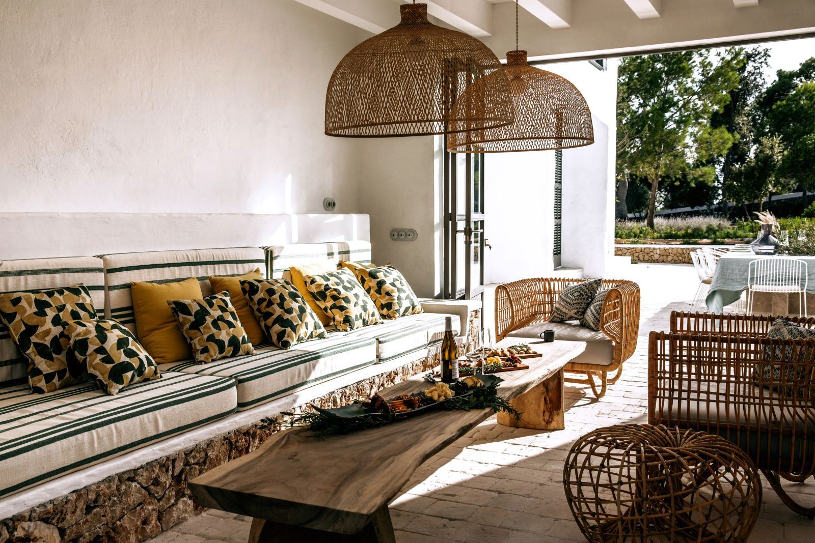 seating bench with white and green cushions and long wooden table four green chairs and a long table with food and wine on the roof terrace at luxury villa Casa Benedicta in Menorca 