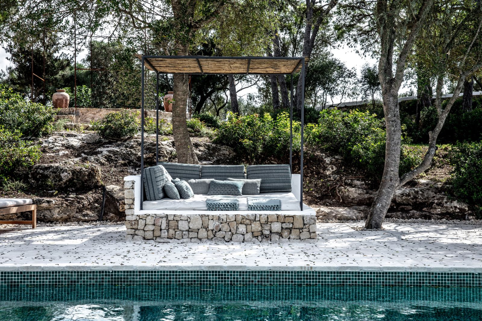 edge of poollllll with sun bed under a canopy four green chairs and a long table with food and wine on the roof terrace at luxury villa Casa Benedicta in Menorca 